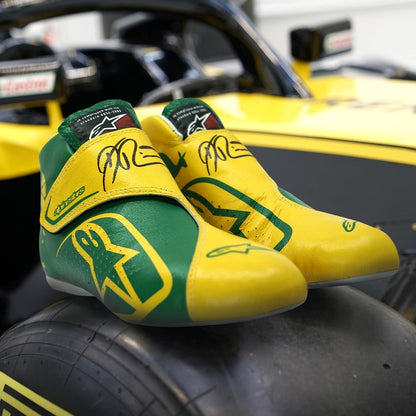 Green and yellow Daniel Ricciardo 2019 Australian Grand Prix F1 racing shoes on a car tire with a blurred race car in the background